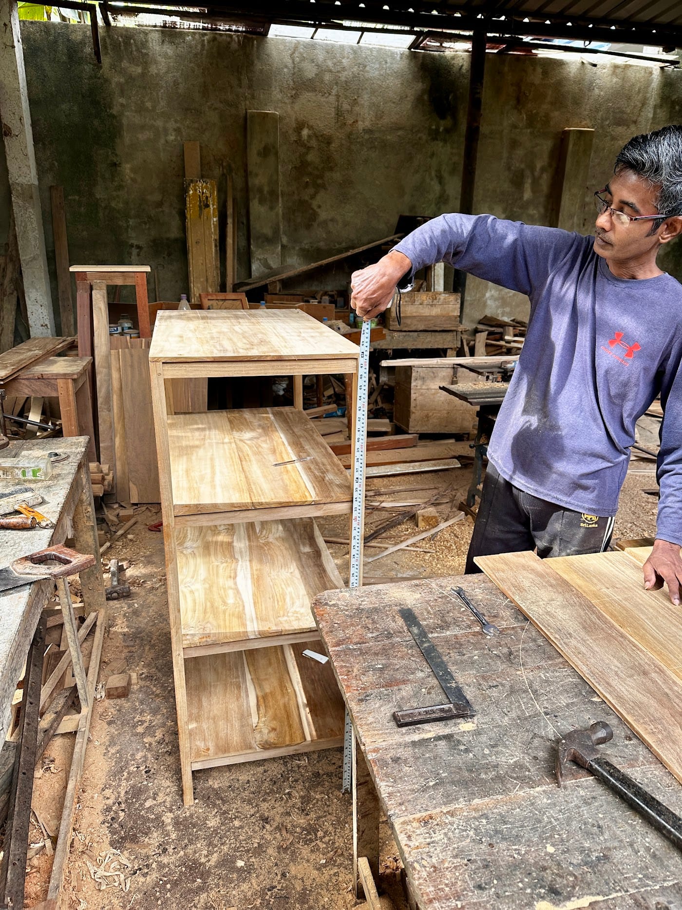 Local carpenter measuring a teak cabinet made for the Kelani retreat house